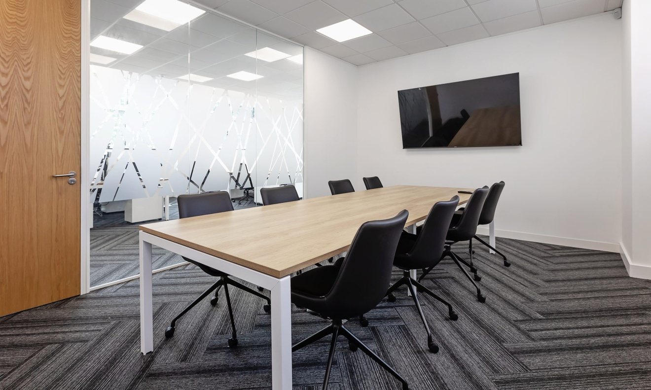 office design in Oxfordshire with glass wall flat screen tv and table surrounded by black chairs