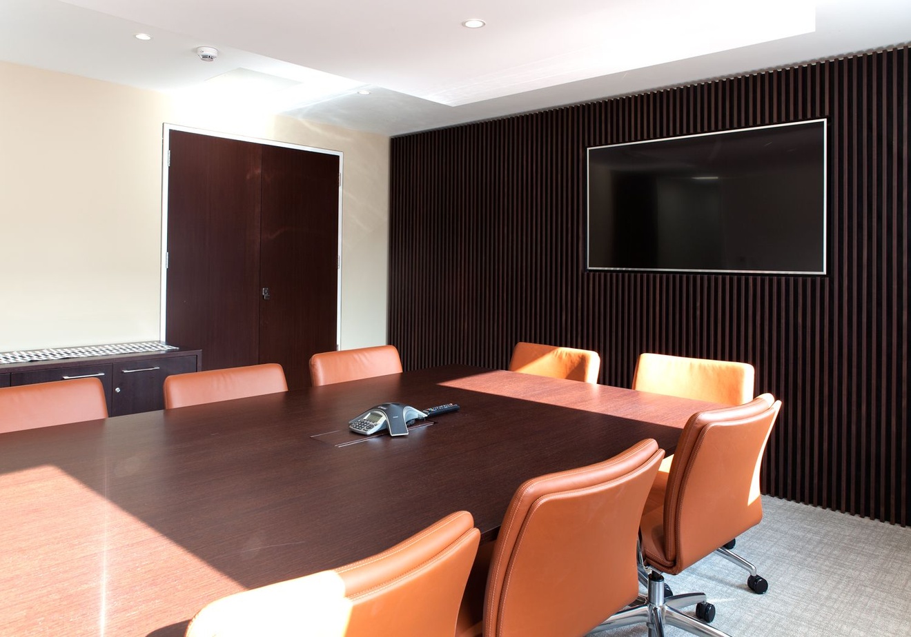 A meeting room with a wooden-slat feature wall, a television and a meeting table.