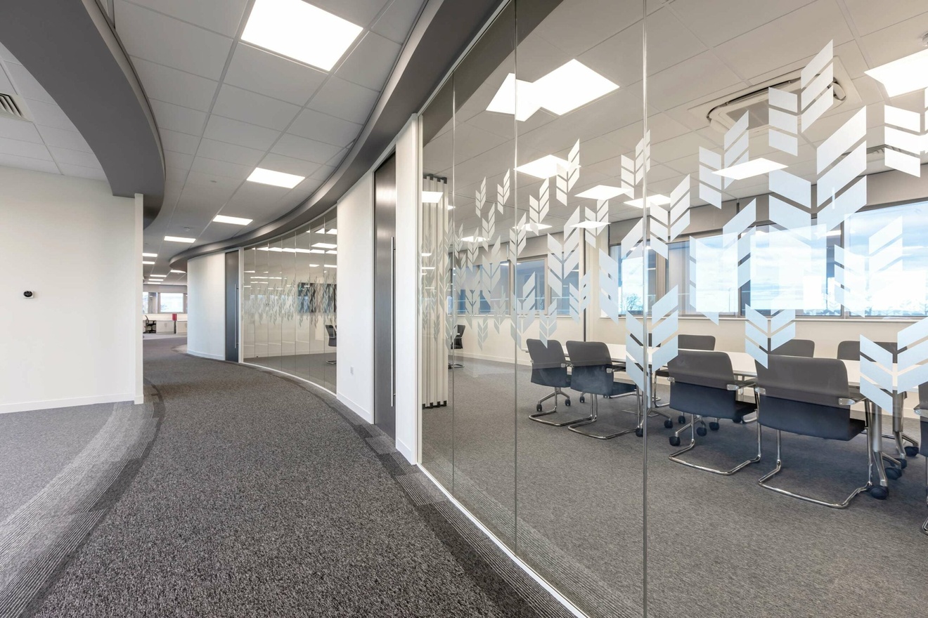 A hallway with private offices on the right side, separated by a glass wall.