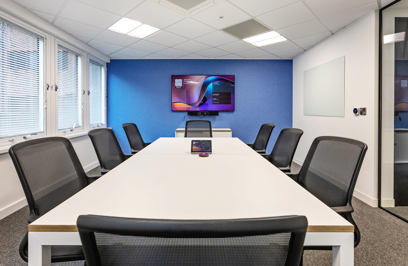 large meeting room with blue and white walls with a large mounted tv with white table and eight chairs