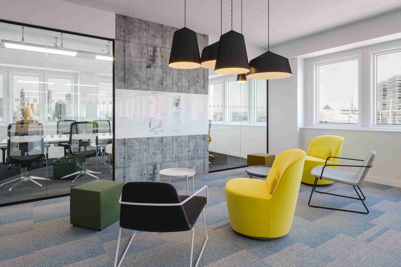 An assortment of chairs pointed towards a wall with a whiteboard on it.