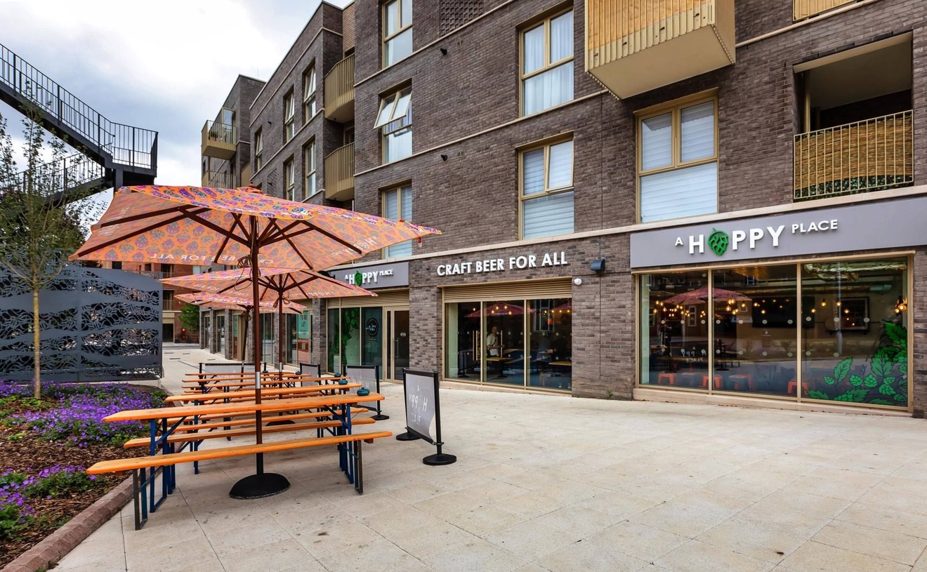 The outside of a bar with benches and umbrellas.