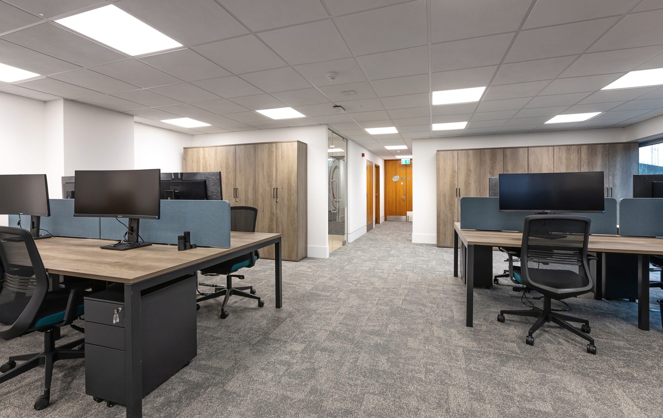 open plan office space with black swivel chairs and computers with blue desk dividers