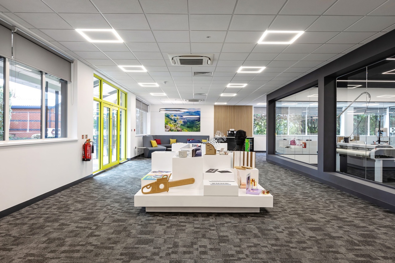 open plan office with grey carpet, sculptured in the centre of the room and sofas in the background