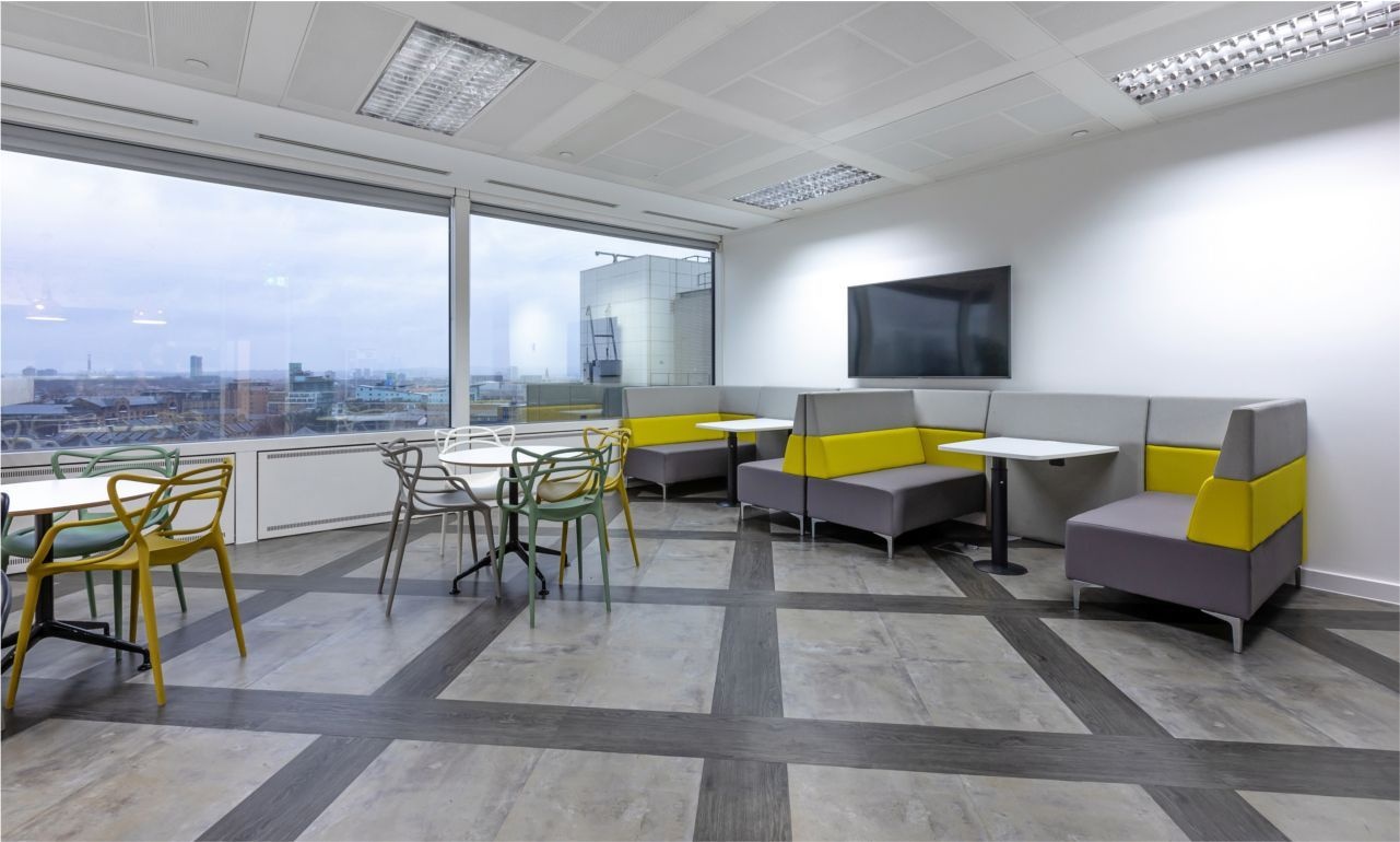 An office breakout space with sofa booths, tables and chairs.