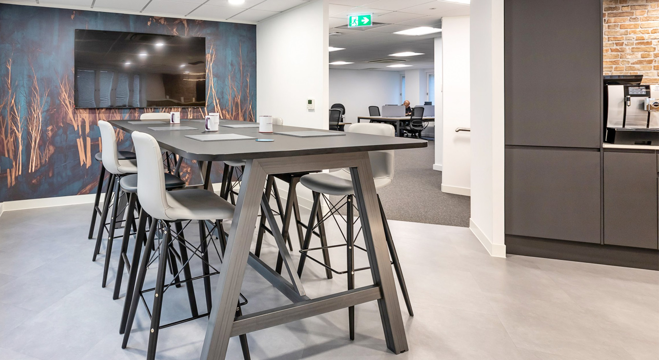 Modern office break area with high table and stools